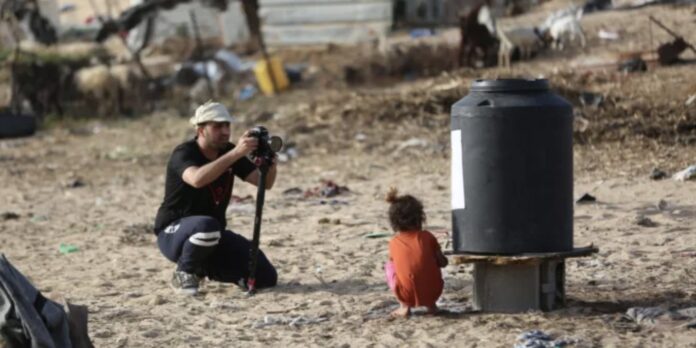 Fotoperiodista trabajando sobre el terreno frente a una niña