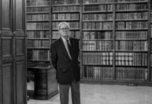 Félix de Azúa: cuando la sociedad se convierte en espectáculo Félix de Azúa de pie en una biblioteca con estanterías de libros