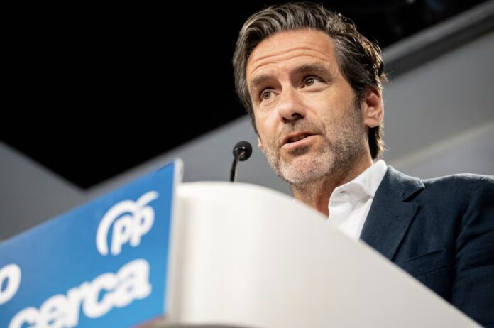 Hombre hablando ante un atril con el logotipo del PP durante una rueda de prensa